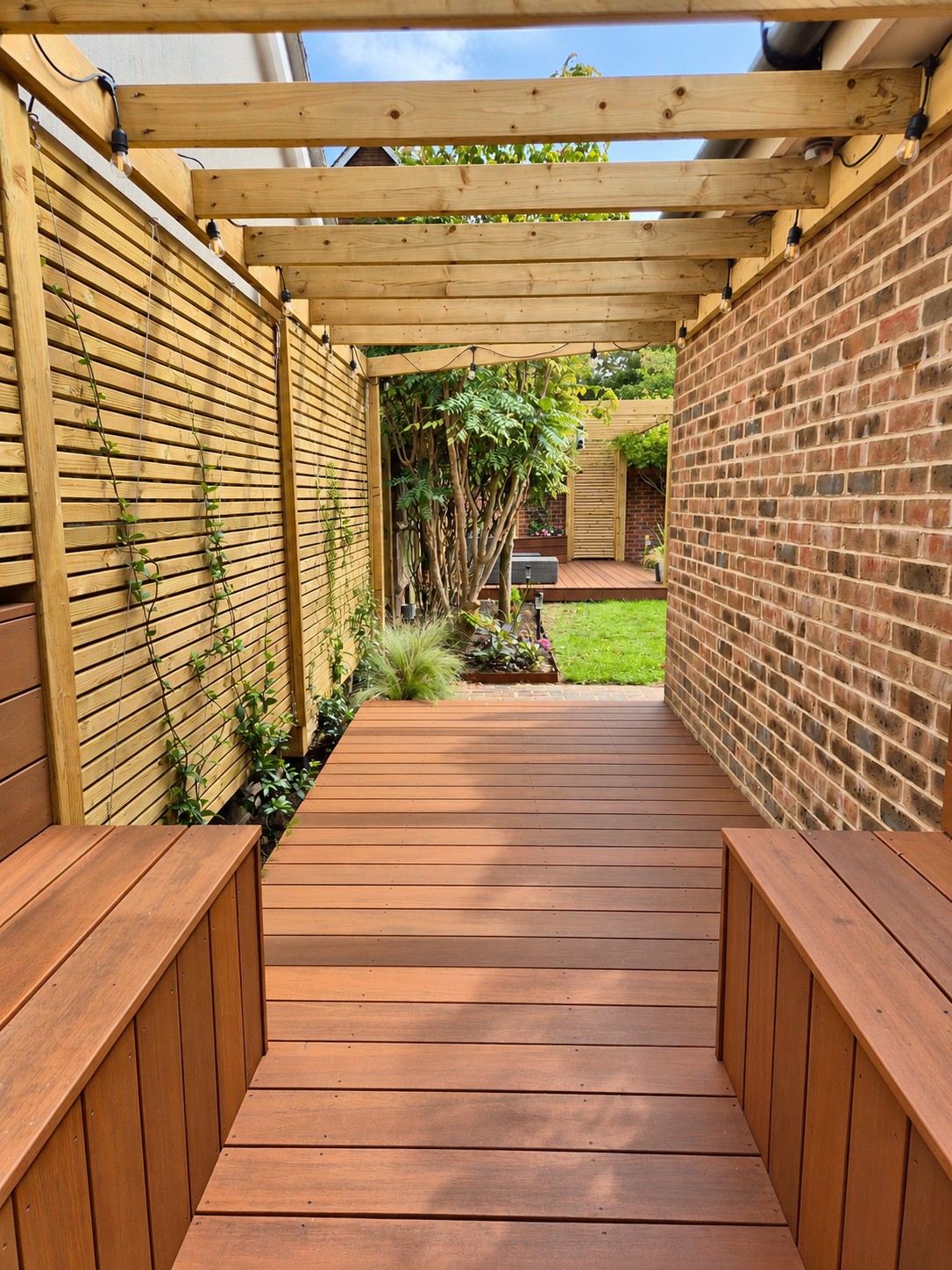Timber pergola walkway with built-in benches and string lights