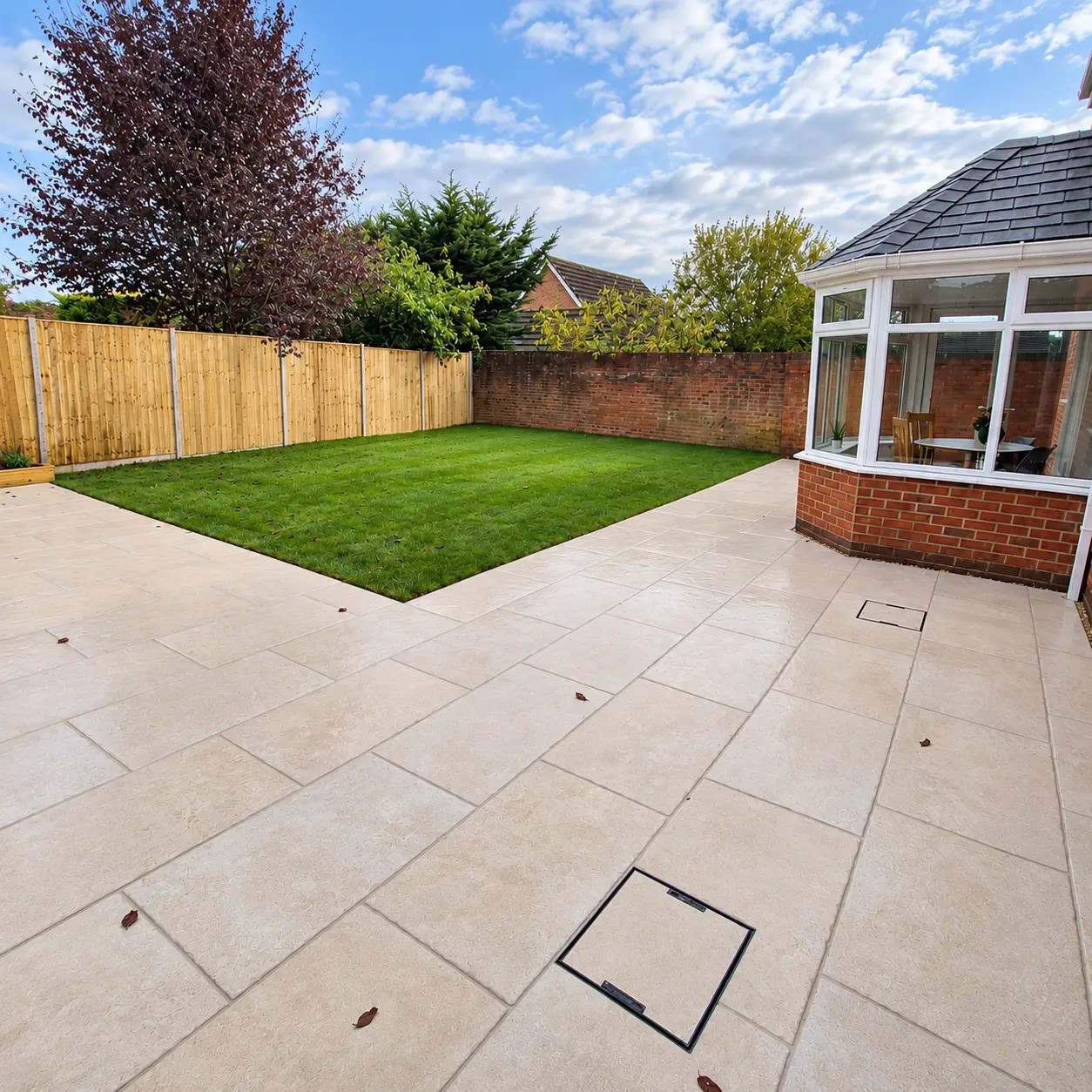 Sandstone paving with a freshly laid lawn and new timber fencing