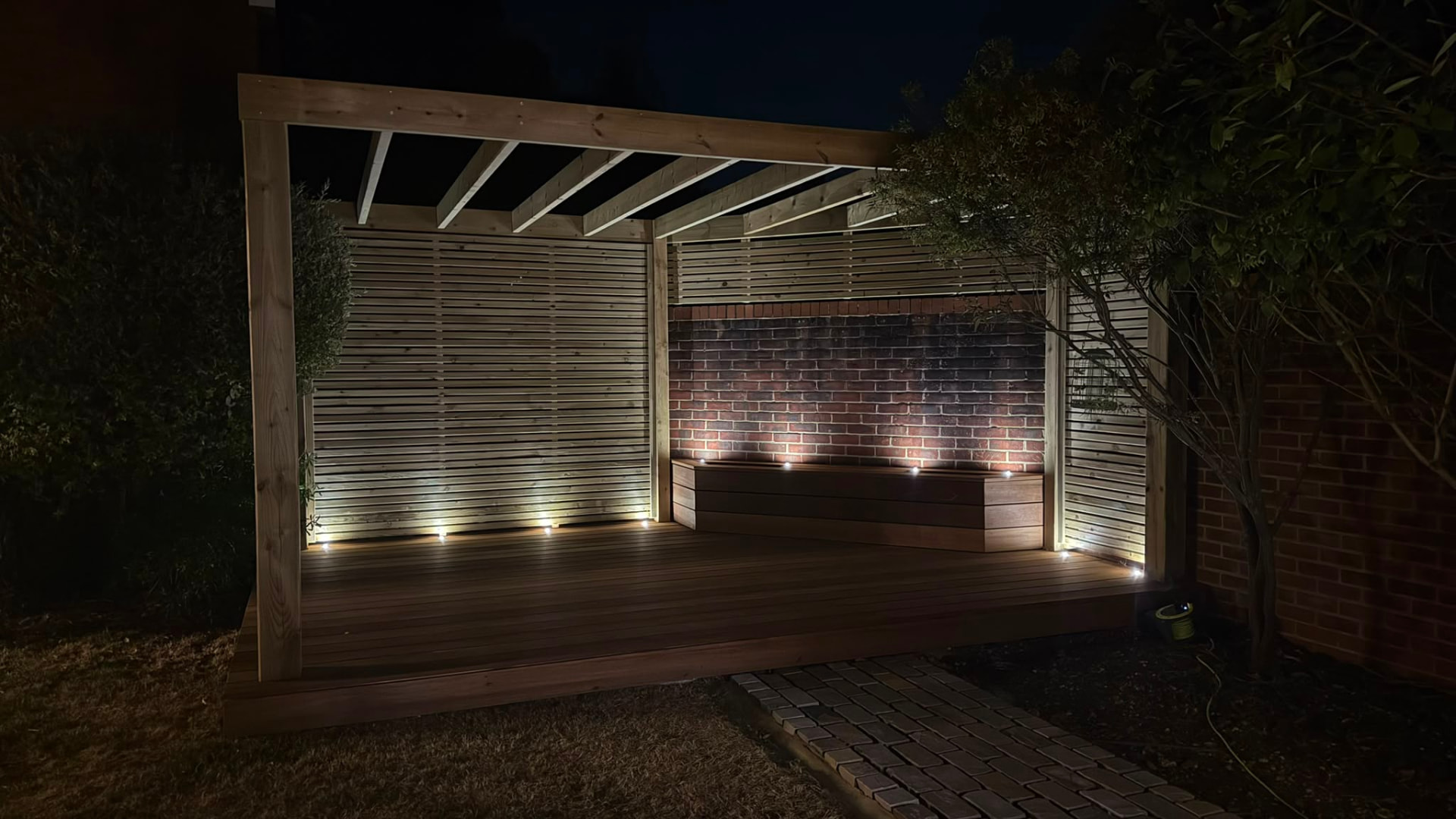 Timber pergola and deck illuminated by garden lights at night